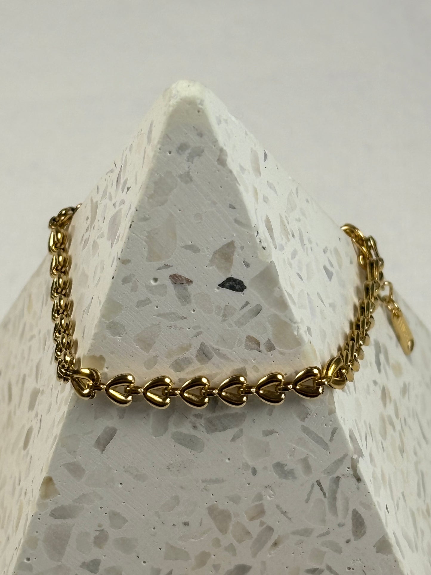Gold chain bracelet on a textured stone surface