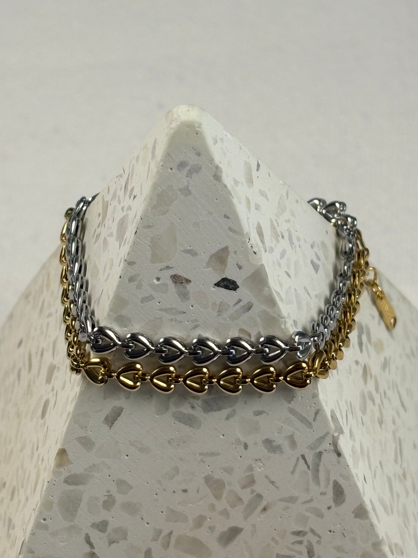 Gold and silver chain bracelet on a textured stone surface