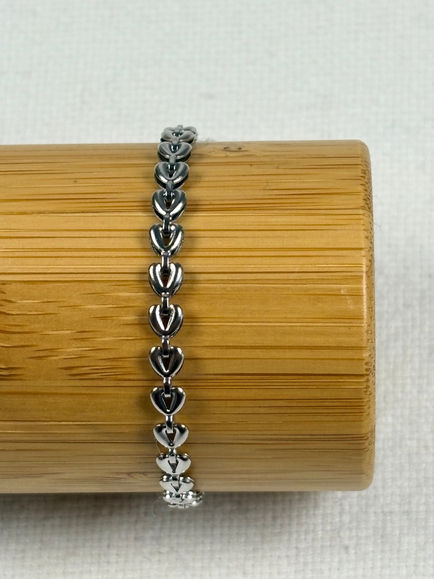 Silver bracelet on a wooden cylindrical stand with a light background