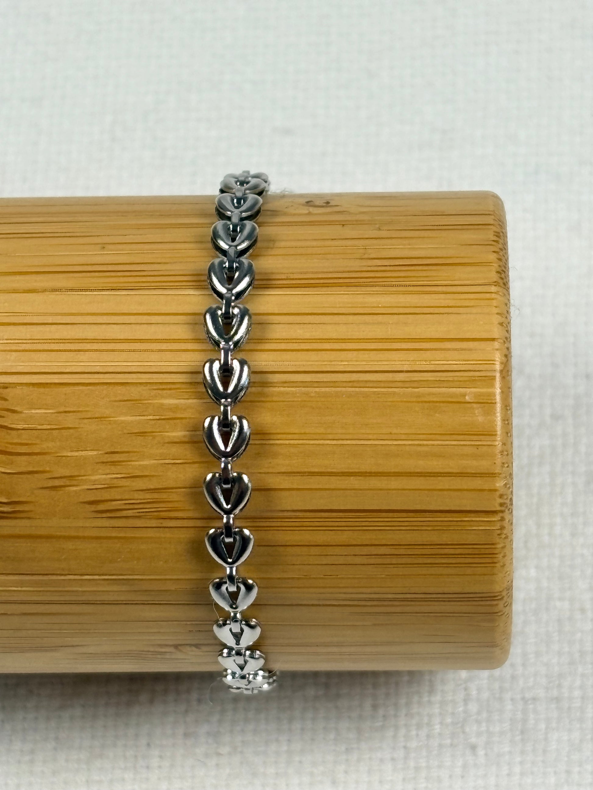 Silver bracelet on a wooden cylindrical stand with a light background