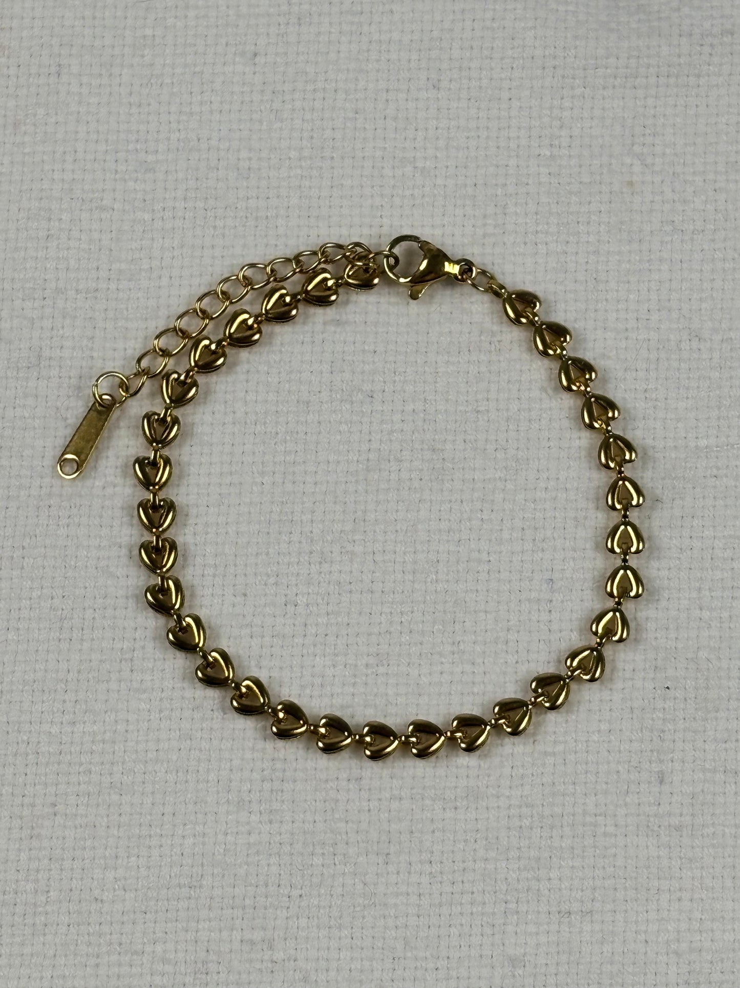Gold chain bracelet on a light gray background