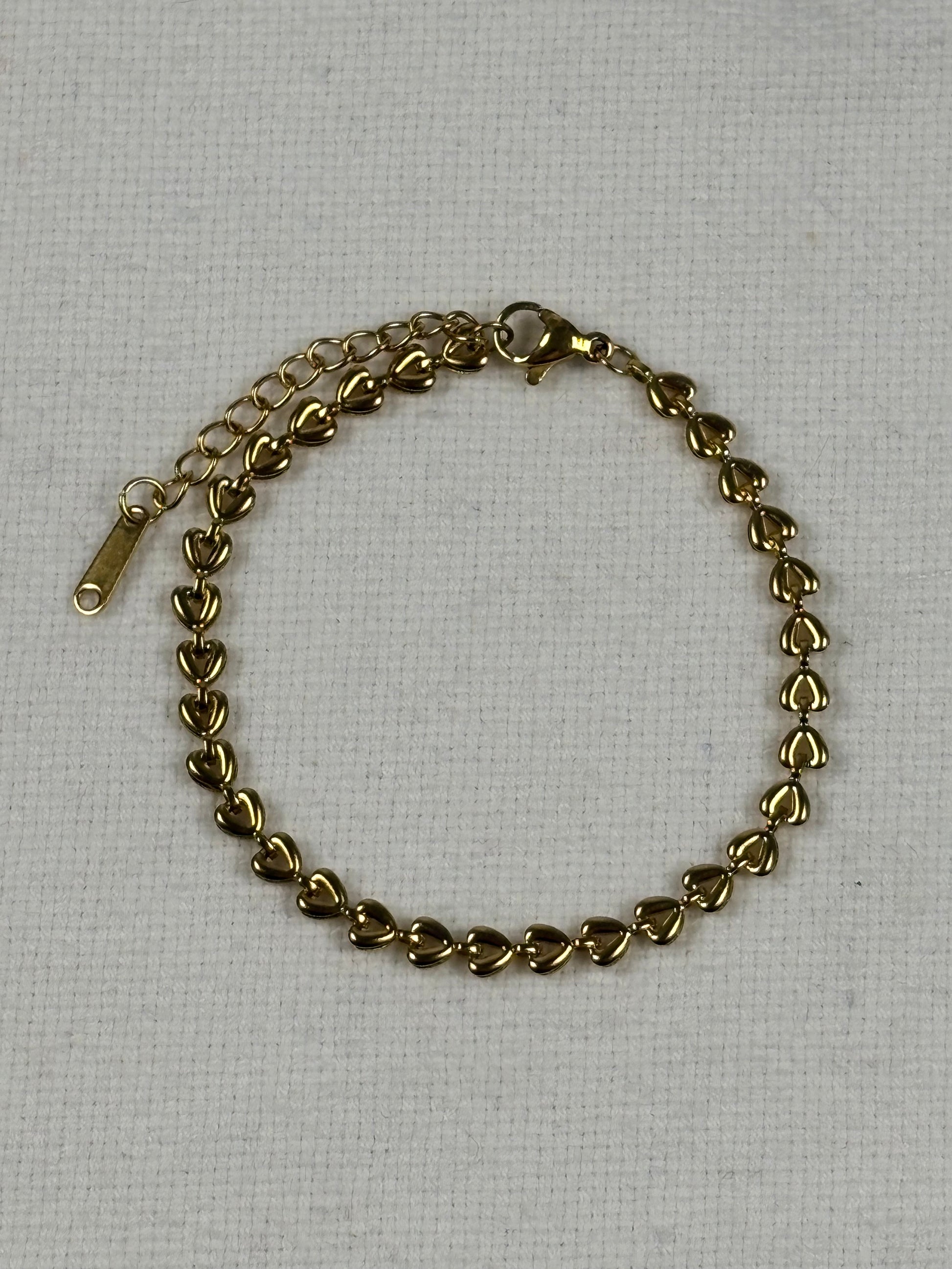 Gold chain bracelet on a light gray background
