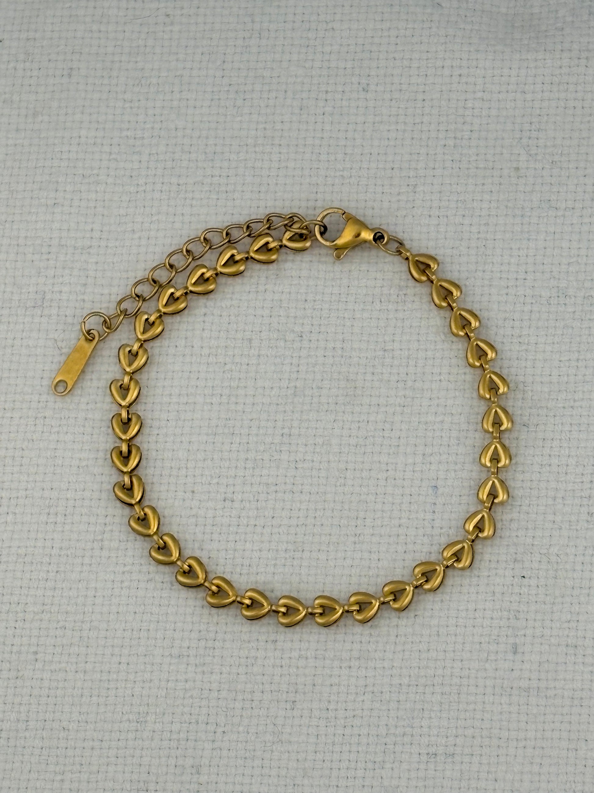 Gold chain bracelet on a textured gray background