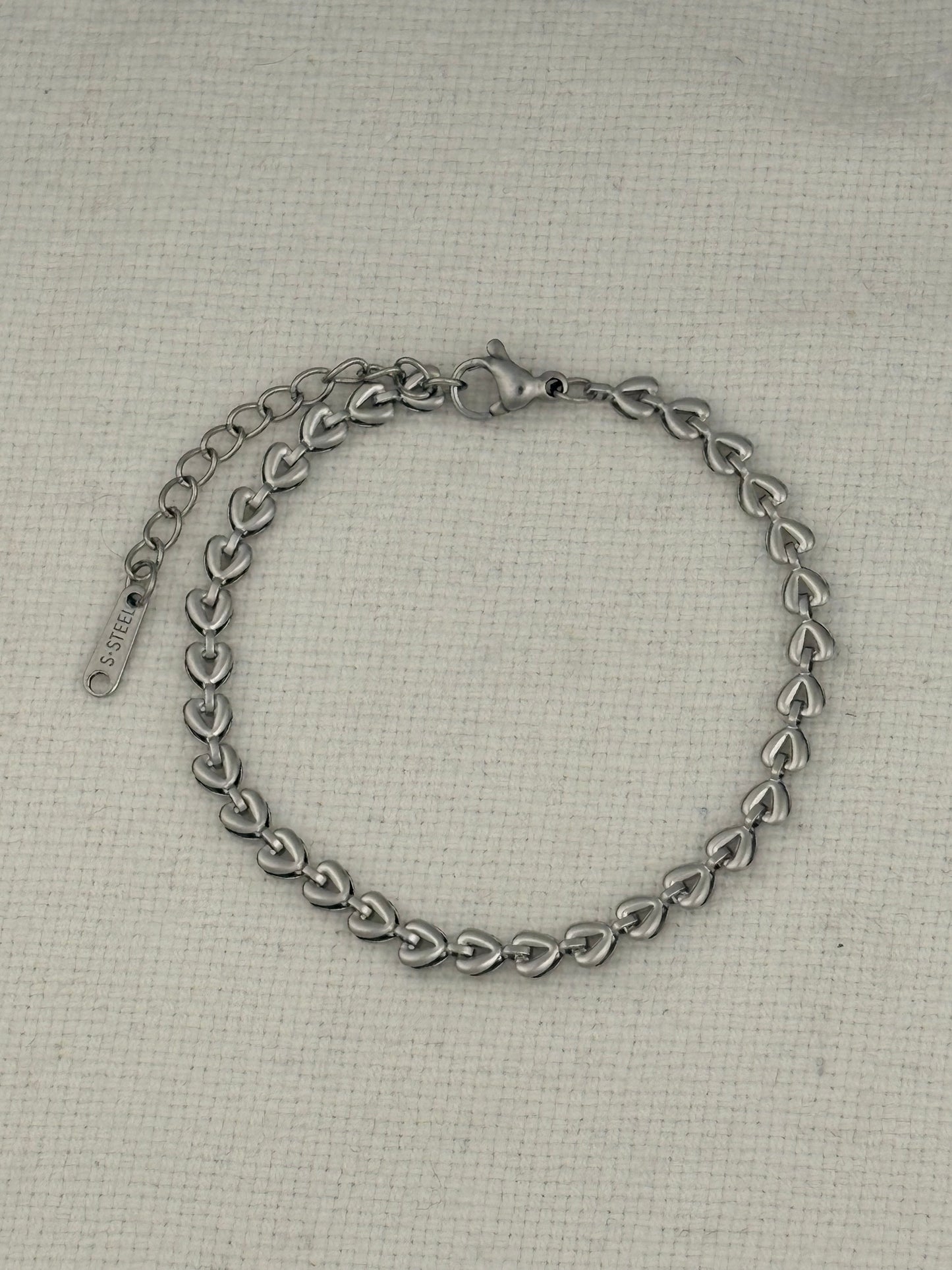 Silver chain bracelet on a textured beige background